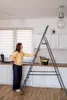 A woman is standing next to a ladder in a kitchen. Podgląd zdjęcia produktu