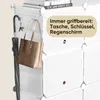 A close-up of a white modular shoe cabinet with a brown tote bag and a black umbrella hanging from hooks on the side. Text overlay highlights the convenience of having items readily available. Produktbild-Vorschau