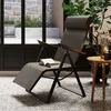 A reclining garden chair with a book on it, placed on a patterned tiled floor next to a small wooden table with a plant and candle. Produktbild-Vorschau
