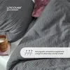 A close-up view of a dark gray musselin bed linen set, with a pillow and a cup of coffee in the foreground. Produktbild-Vorschau