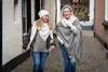 Two women walking down a cobblestone alleyway, both wearing winter clothing and scarves. Produktbild-Vorschau