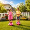 Zwei Kinder, ein Junge und ein Mädchen, spielen mit rosa Pogo-Bällen in einem sonnigen Hinterhof Podgląd zdjęcia produktu