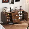 A wooden sideboard with various items on and inside it, including a coffee machine, wine bottles, cups, and plates. A robot vacuum cleaner is visible underneath. Anteprima dell’immagine prodotto