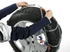 A person is shown installing snow chains on a car tire. Produktbild-Vorschau
