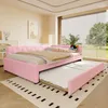 A pink upholstered daybed with a trundle bed pulled out, set in a well-lit bedroom with a large window. Podgląd zdjęcia produktu