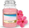 A Yankee Candle jar with a label showing a beach scene, accompanied by two pink hibiscus flowers. Podgląd zdjęcia produktu