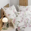 A close-up view of a bed with floral patterned bedding and a bedside lamp. Voir les images du produit