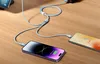 Two smartphones and a power bank are connected to a multi-port charging cable on a wooden surface. Produktbild-Vorschau