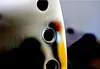 A close-up view of a metal surface with several holes, showing iridescent colors around one of the holes. Náhled obrázku produktu