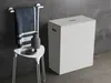 A modern bathroom setting with a laundry basket, stool, vase, and towel. Voir les images du produit