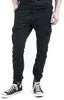 A person wearing black cargo jogging pants and black high-top sneakers, shown from the waist down against a white background. Anteprima dell’immagine prodotto