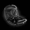 An open black sandwich toaster against a black background. Produktbild-Vorschau