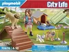 A Playmobil dog trainer playset is displayed on its packaging, featuring a girl with dogs, a dog house, and agility equipment. Produktbild-Vorschau