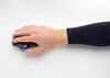 A hand using a black trackball mouse with a blue ball on a white surface. Anteprima dell’immagine prodotto