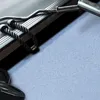 A close-up shot of gym equipment, including a barbell and a rope attachment, resting on a textured surface. Podgląd zdjęcia produktu