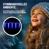 A young girl looking up at blue icicle lights in a snowy setting. Produktbild-Vorschau