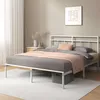 Weißes Metallbett mit Pfirsichfarbener Decke in einem hellen Raum mit Teppich und Wandkunst.
 Produktbild-Vorschau
