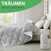 A neatly made bed with a gray comforter and white pillows, with a storage bag for the comforter in the foreground. Produktbild-Vorschau