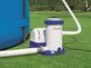 A pool filter pump system connected to a blue inflatable pool, set up on a grassy lawn. Voir les images du produit