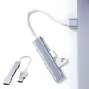 A silver USB hub with multiple ports is shown connected to a laptop or computer. Another smaller USB hub is placed in the foreground. Produktbild-Vorschau