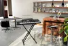 A modern living space with a keyboard on a stand, a table and chairs, and a bar area. Náhľad obrázku produktu