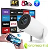 A white projector is shown in front of a screen displaying various streaming service logos. A smartphone is held in the foreground, showing a car on its screen, with a Wi-Fi symbol between the phone and the projector. An Android mascot and the text 'ANDROI Produktbild-Vorschau