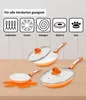 A set of orange and white ceramic pans with glass lids are displayed on a wooden surface, with icons indicating compatibility with different stovetops. Produktbild-Vorschau