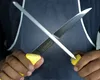A close-up shot of hands holding a knife and a sharpening steel, crossed over each other. Produktbild-Vorschau