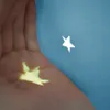 A hand holding a star-shaped light projection against a blue background. Voir les images du produit