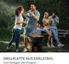 People enjoying a barbecue outdoors with a fire pit and grill. Produktbild-Vorschau