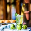 A refreshing drink with limes and mint, surrounded by limes and a tray of citrus fruits in the background. Náhled obrázku produktu