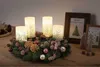 A Christmas advent wreath with four LED candles, pinecones, ornaments, and small decorative trees on a wooden table. Produktbild-Vorschau