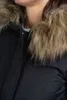 A close-up shot of a person wearing a black winter jacket with a fur-lined hood. Produktbild-Vorschau