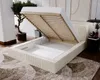 A beige upholstered bed with its mattress and frame lifted to reveal storage space underneath. Produktbild-Vorschau