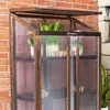 A close-up view of a wooden greenhouse with clear polycarbonate panels, filled with plants and small pots. Voir les images du produit