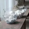 Two clear glass bowls filled with white stones and white candles sit on a wooden surface. Anteprima dell’immagine prodotto