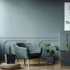 A modern living room with a plush armchair and several potted plants. Náhled obrázku produktu