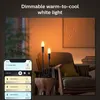 A smartphone app interface is shown in the foreground, controlling two candle-shaped LED lights in a living room setting. Produktbild-Vorschau