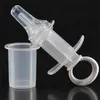 A clear product shot of a plastic feeding syringe and a measuring cup against a black background. Produktbild-Vorschau