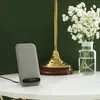 A wireless charger is placed on a marble table next to a lamp and a vase of flowers. Produktbild-Vorschau