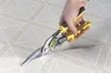 A hand is using tin snips to cut a roll of wallpaper with a geometric pattern. Anteprima dell’immagine prodotto
