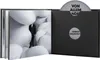 An open book-style case with a CD and a book inside. The book has a person in a suit standing among white inflatable shapes. Voir les images du produit