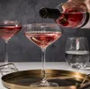 A bottle of rosé wine is being poured into a set of elegant coupe glasses on a tray. Produktbild-Vorschau