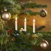 Close-up of battery-operated Christmas tree candles with a flame effect, ornaments, and pinecones on a Christmas tree. Produktbild-Vorschau
