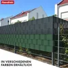 A fence with green and dark gray privacy screen inserts, with houses in the background. Podgląd zdjęcia produktu