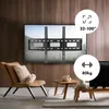 A living room scene with a TV wall mount installed on a wooden wall, a chair, and coffee tables. Anteprima dell’immagine prodotto