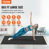A woman is doing a side plank on a large black exercise mat in a room with furniture. Voir les images du produit