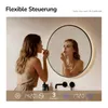 A woman applying makeup in front of a lighted mirror in a bathroom. Náhled obrázku produktu