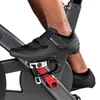 A close-up shot of a person's foot wearing a black cycling shoe, clipped into the pedal of a stationary bike. Produktbild-Vorschau
