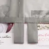 Close-up of a grey fabric curtain with loops, layered over magazine pages with floral and text imagery. Produktbild-Vorschau